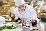 Chef putting mint with her chocolate cake in the kitchen