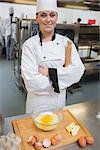 Smiling pastry chef with rolling pin making dough