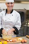 Smiling woman preparing the dough in the kitchen