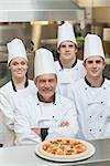 Smiling group of Chef's with a pizza on the counter