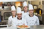 Happy group of Chef's standing behind pizza on counter