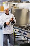 Smiling chef holding a pepper mill in kitchen