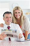 Smiling couple with newspaper and tablet pc in the kitchen before work