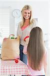 Mother and daughter unpacking grocery bag in the kitchen