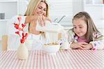 Woman pouring milk into a glass for daughter and smiling