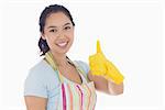 Happy woman giving thumbs up in yellow rubber gloves and apron