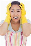 Stressed woman wearing rubber gloves and apron with her hands on head and screaming