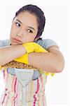 Fed up woman wearing apron leaning on the mop