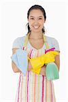 Woman standing with hands crossed holding cleaning products and smiling