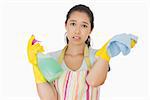 Weary woman wearing apron and gloves with spray bottle and rag