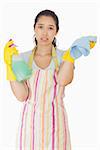 Overworked woman holding rag and spray bottle in apron and rubber gloves