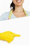 Smiling woman in rubber gloves and apron standing behind board and pointing