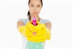 Serious woman pointing a spray bottle at the camera on a white background