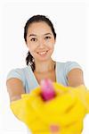 smiling woman pointing spray bottle at the camera on a white background