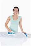 Smiling woman ironing on an ironing board in a white background