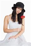 Woman holding flower in a polka dot dress on white background