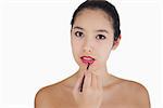 Woman putting on lipstick with a brush on white background