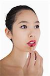 Woman putting on pink lipstick on white background