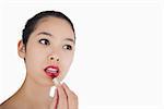 Woman applying lipstick on white background