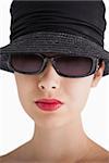 Woman wearing hat and sunglasses with red lips against white background