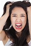 Woman screaming and pulling her hair out on white background
