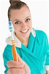 Woman with bathrobe showing her toothbrush in the white background