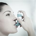 Woman using an asthma inhaler as prevention