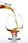 cognac pour into the glass over white background