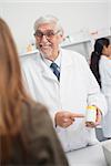 Smiling male pharmacist pointing at drugs in a hospital