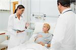 Male and female doctor standing next to a patient in a hospital bed