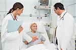 Two practitioners standing next to a patient in a hospital room