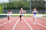 Female athletes running towards finish line on track field