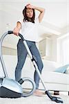 Tired woman with vacuum cleaner at home