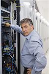 Technician looking up from adjusting server wires in data center