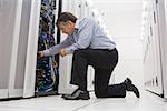 Technician kneeling while repairing the server with his hands in the data center