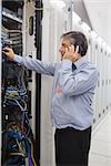 Male technician repairing the server case while phoning in data center