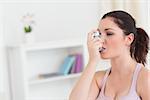 Brunette woman using asthma inhaler in living room