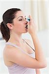 Brunette using asthma inhaler in living room