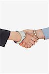 Handcuffed business partners shaking hands over white background