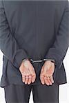 Rear view of businessman with handcuffs standing over white background