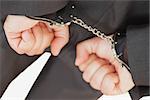 Cropped image of businessman with handcuffs clencing fists against white background