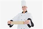 Portrait of happy female chef with rolling pin standing against whhite background