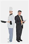 Full length portrait of happy businessman holding digital tablet and female chef with frying pan over white background