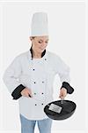 Happy female chef using spatula and frying pan aover white background
