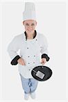 High angle view of female chef with spatula and frying pan over white background