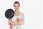 Portrait of young woman in apron holding frying pan over white background