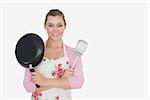 Portrait of beautiful young woman holding frying pan and spatula against white background