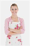 Portrait of young woman in apron with arms crossed over white background