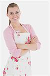 Beautiful young woman in apron standing with arms crossed over white background