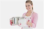 Portrait of happy young maid holding cooking utensil over white background